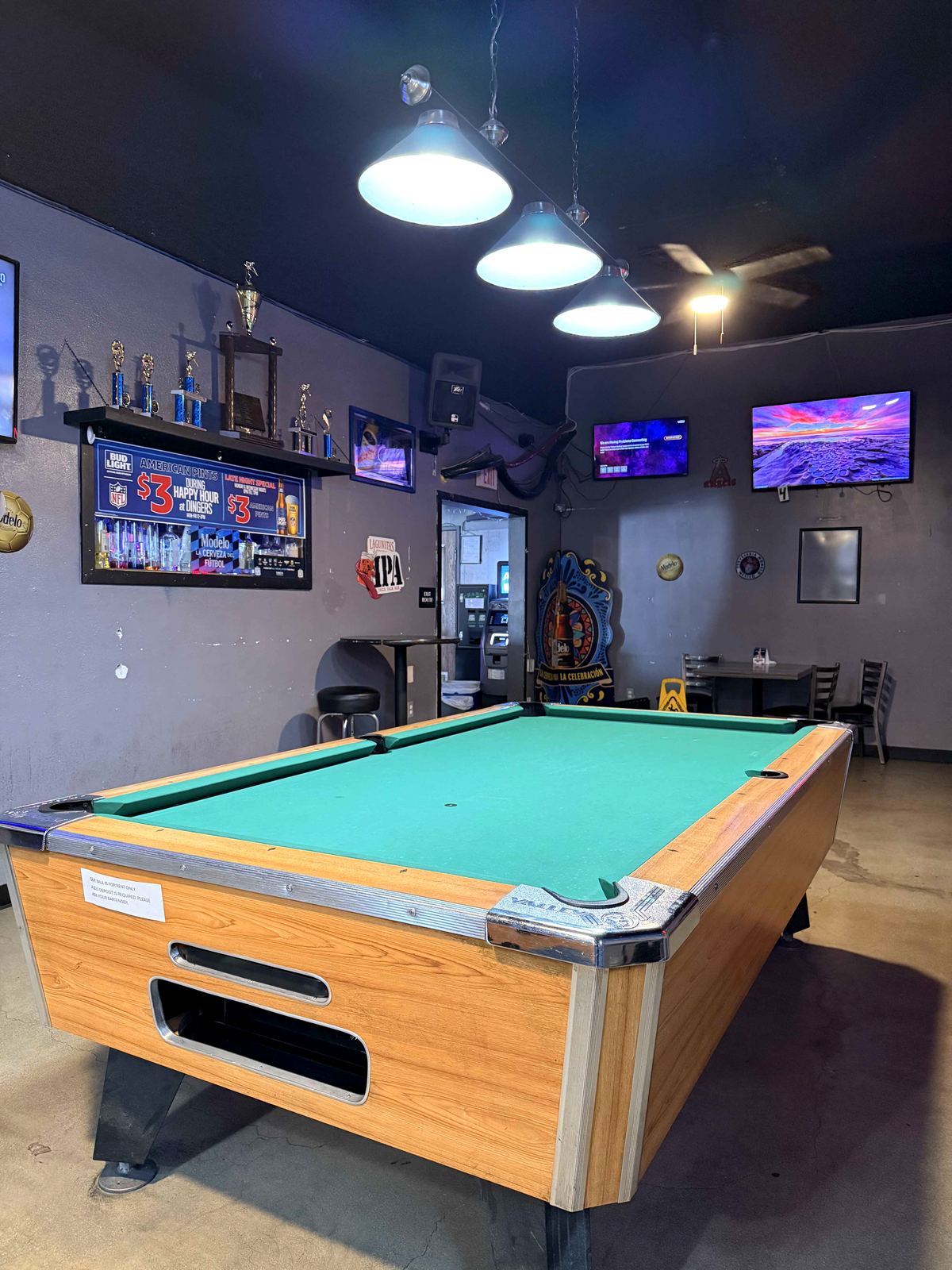 Pool league trophy shelf at Dingers Sports Bar. Multiple gold and silver trophies, IPA neon sign beside the shelf.